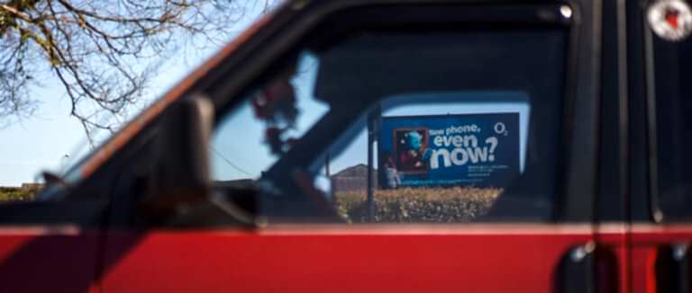 O2 advertisement viewed through red car