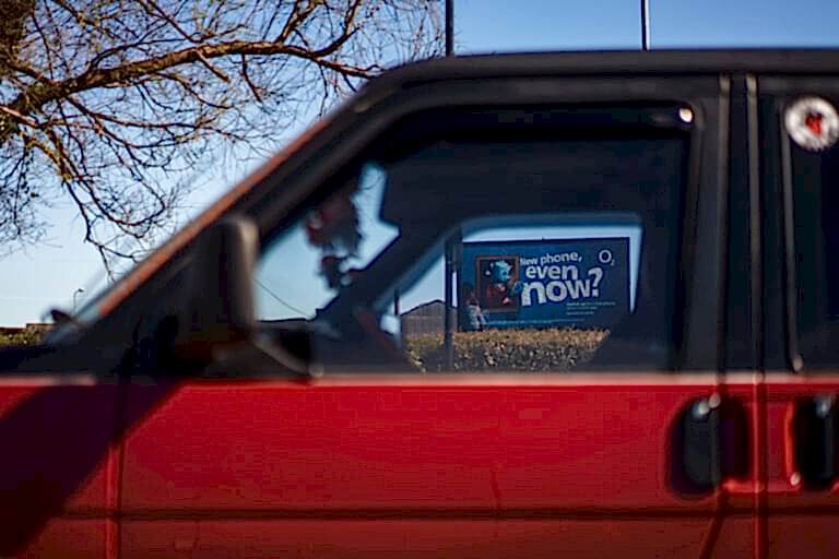 O2 advertisement viewed through red car